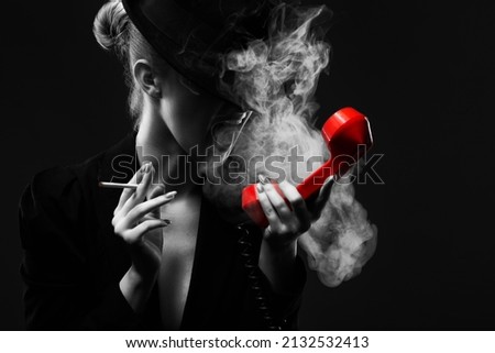 A mysterious woman in a black suit and hat smokes a cigarette, screaming while talking on the phone.Black and white photo.