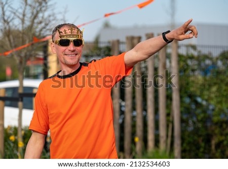 Dutchman celebrating kings day on the road during a street party dressed in orange in Holland the Netherlands. Koningsdag is a traditional festival to celebrate the Dutch royal family. Dutch bunting.