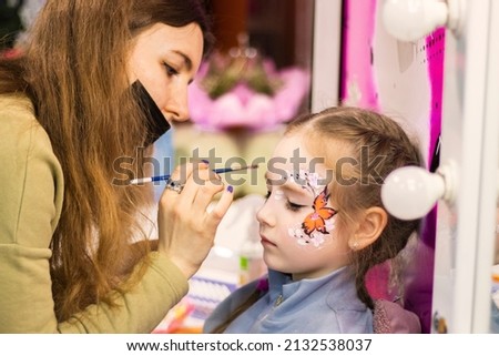 selective focus. A makeup artist works. childrens makeup face paint drawings Girls face painting. Little girl having face painted on birthday party. closed eyes. High quality photo