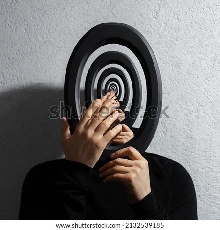 Enigmatic surrealistic optical illusion, young man holding round frame.