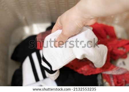 The hand throws or takes dirty white laundry into the dirty clothes basket, preparation for washing clothes, washing white socks. Royalty-Free Stock Photo #2132553235