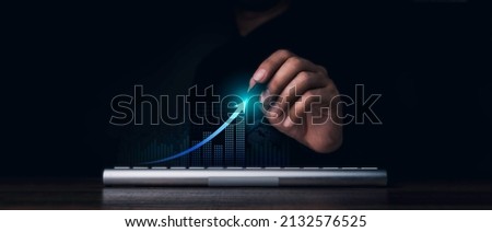 Investment technology, financial, return on investment - ROI concepts. Increasing arrow, the exponential curve of progress in business performance over charts draws by pen in hand on dark background. Royalty-Free Stock Photo #2132576525