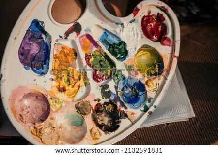 A woman's hands mixing paints on a palette board. Preparing to paint a picture. Artistic tools. The creative process.