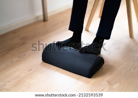 Worker Using Footrest To Reduce Back Strain And Feet Fatigue Royalty-Free Stock Photo #2132593539