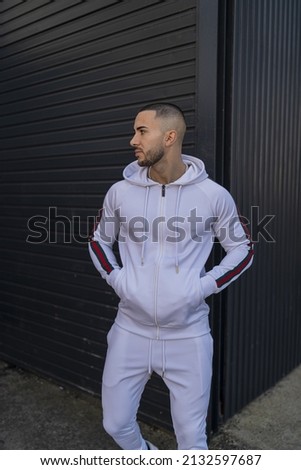 A vertical shot of a young cool hip male in a white sweatsuit posing Royalty-Free Stock Photo #2132597687