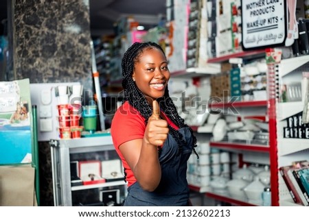 Positive dark skinned female sale girl posing proudly in cosmetic supermarket given a thumbs up