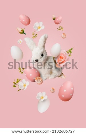 Easter bunny, colorful eggs and spring flower flying in the air against pastel pink background. Minimal Easter holiday concept.
