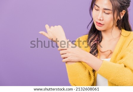 Portrait of Asian beautiful young woman sad with wrist pain from carpal tunnel syndrome, female hand injury feeling pain, studio shot isolated on purple background, Health care and medical concept