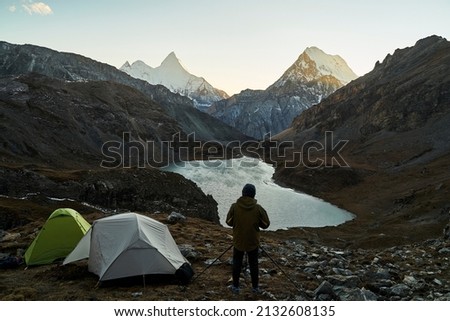 asian camper photographer taking a picture of mountain and lake in yading national park, daocheng county, sichuan province, china