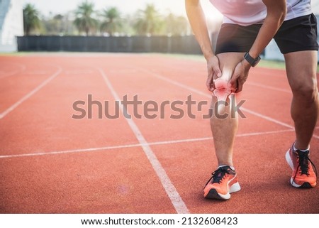 Injured by fitness concept. Man using hands on his knees while working on the street in a park with copy space for text. runner have knee ache due to Runners Knee or Patellofemoral Pain Syndrome. Royalty-Free Stock Photo #2132608423