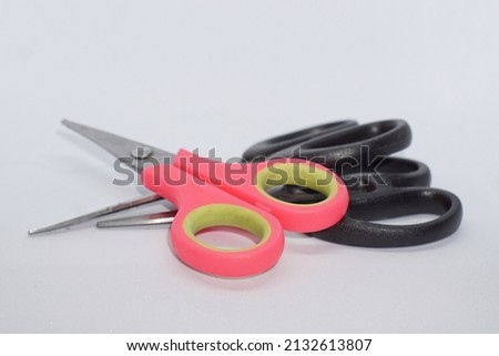 pile of pink and black scissors on a white background