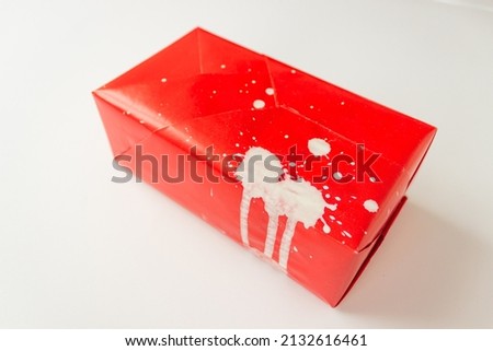 Gift box is wrapped in red paper in splashes of white paint. Isolated on white background.