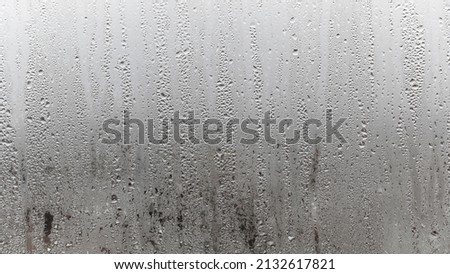Close up water drop on grey background, misted glass with droplets of water draining down. Dripping Condensation Royalty-Free Stock Photo #2132617821