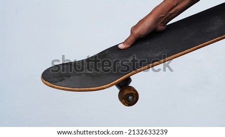 Right hand carrying skateboard. Concept on a white background.                               