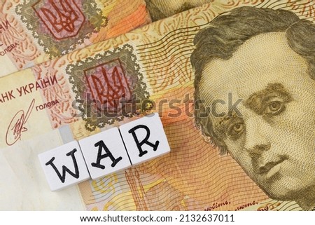The sentence "war" composed of letters on the background of Ukrainian banknotes. Photo taken under artificial, soft light