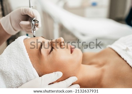 Beautiful brunette getting oxygen face therapy in a beauty salon. Professional skin care treatment. Royalty-Free Stock Photo #2132637931