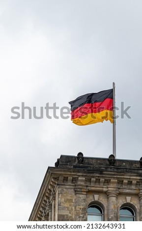 Canvas for social media news: German flag waving in the wind on the German parliament, clouds in background; picture in vertical Format for phones (social media)
