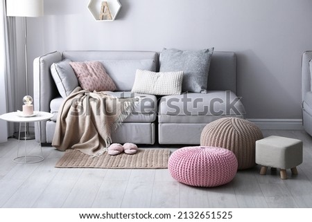 Stylish poufs and ottoman near sofa in living room. Interior element Royalty-Free Stock Photo #2132651525