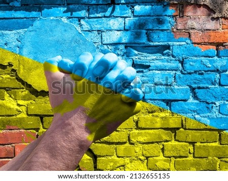 Brick wall with praying hands in Ukraine colors