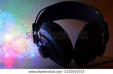 Bright garland next to the headphones for sound production, headphones close-up in the red lighting of colored lights, professional headphones  Royalty-Free Stock Photo #2132655553