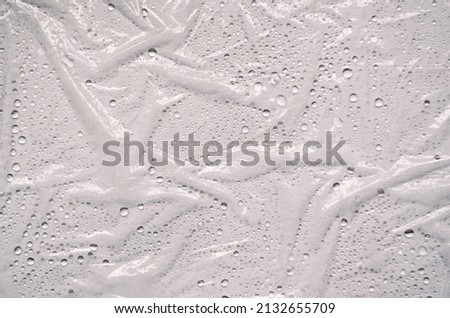 Plastic wrap texture for overlay. wrinkled stretched plastic effect. transparent plastic wrap on white background. Food rumpled cellophane wrap. With water drops