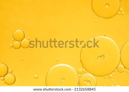 Golden yellow abstract oil bubbles or face serum background. Oil and water bubbles macro photography.