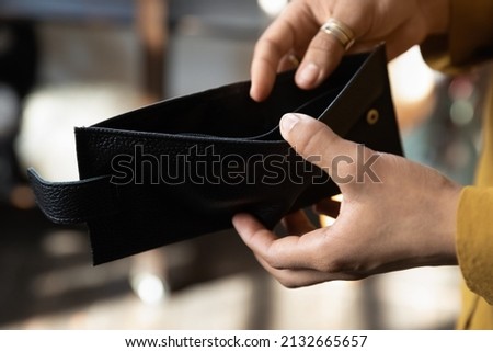 Hands of young African woman opening empty black wallet, leather purse without money. Financial problems, cash crisis, bankruptcy, low income, finance unemployment concept Royalty-Free Stock Photo #2132665657