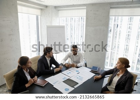 Above view focused skilled diverse business people of different ages discussing marketing research results reports, developing project growth strategy or brainstorming ideas in modern boardroom. Royalty-Free Stock Photo #2132665865