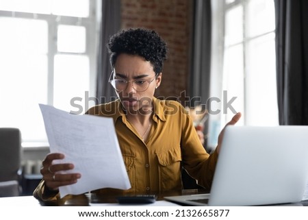 Worried frustrated Black professional woman reading paper notification with bad news, getting problems, dismissal, bankruptcy. Student girl receiving document from college, rejection notice Royalty-Free Stock Photo #2132665877