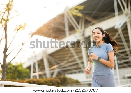 Attractive beautiful woman wearing sportswear running at sport stadium. Fit woman jogging outdoor. Workout exercise in the morning. Healthy and active lifestyle concept. Royalty-Free Stock Photo #2132673789