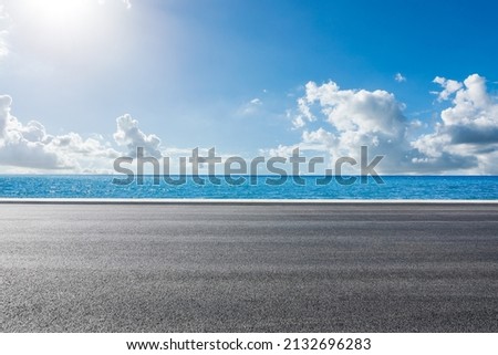 Empty asphalt road near the lake under blue sky Royalty-Free Stock Photo #2132696283