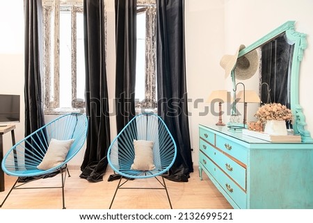 Corner of a bedroom with a blue wooden coquette with a mirror and matching armchairs