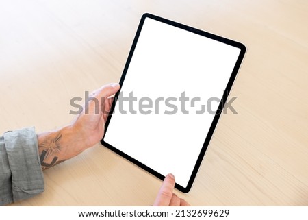 Person holding tablet computer vertically in hands, blank white screen mockup
