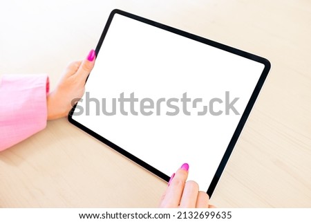 Woman holding tablet computer in hands, blank white screen mockup