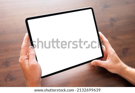 Person holding tablet computer in hands, blank white screen mockup