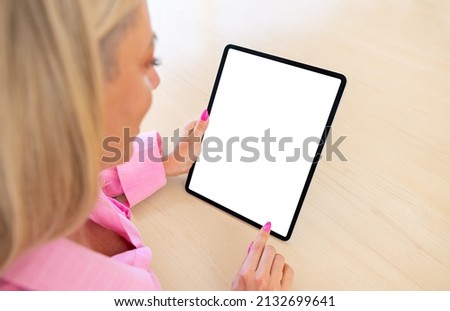 Woman holding tablet computer vertically, blank white screen mockup
