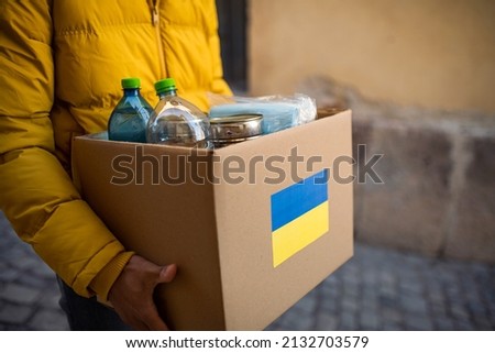 Close up of volunteer cyrrying box with Humanitarian aid for Ukrainian refugees in street Royalty-Free Stock Photo #2132703579