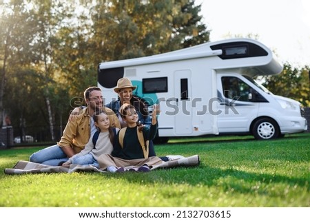 Happy young family with two children ltaking selfie with caravan at background outdoors. Royalty-Free Stock Photo #2132703615