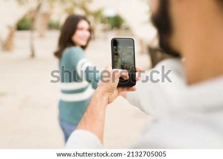 Close up of a loving boyfriend taking a photo of his beautiful girlfriend with a smartphone 