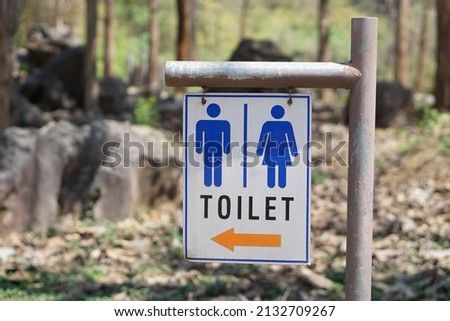 TOILET sign with male ,female and arrow symbols to show the way to toilet at the park. Concept : General sign in daily life that we can see at public places. Traffic sign for toilet.
