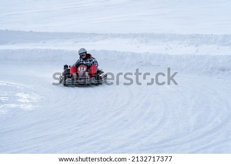 Go karting on icy track in winter. Young adult karting driver in action on outdoor icy track covered with snow Royalty-Free Stock Photo #2132717377