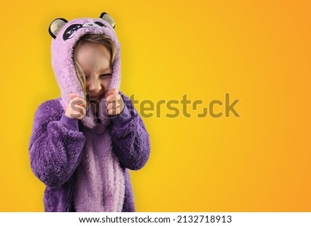 Little girl toddler child wear hooded purple pajamas smiling on isolated yellow  Royalty-Free Stock Photo #2132718913