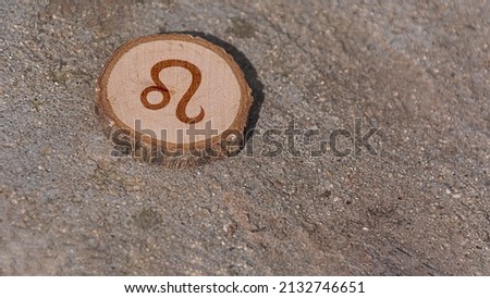 Close-up shot of a piece of wood with a zodiac sign engraved on it, especially the leo sign