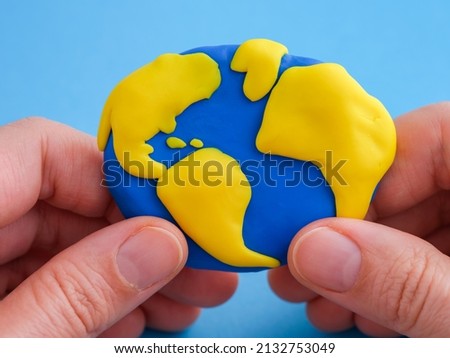 A woman holding the planet Earth in her hands. The planet Earth is made out of polymer clay.