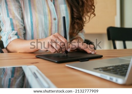 Close Up Photo of Woman Hands Drawing Something on a Graphic Tablet and Laptop Computer while Sitting at Home Office Desk