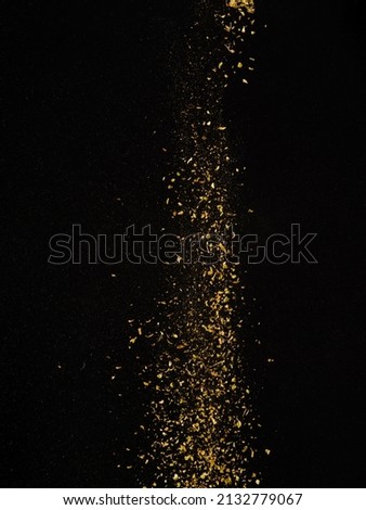 Golden stream of spices in frozen flight on a black background. Abstraction. Minimalism. Advertising, banner. Restaurant and home cooking, supermarket, cafe. hotel.