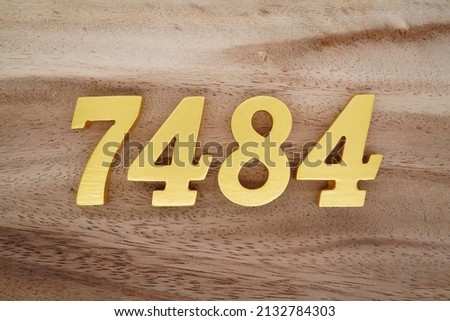 Wooden  numerals 7484 painted in gold on a dark brown and white patterned plank background.