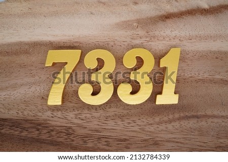 Wooden  numerals 7331 painted in gold on a dark brown and white patterned plank background.