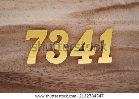 Wooden  numerals 7341 painted in gold on a dark brown and white patterned plank background.