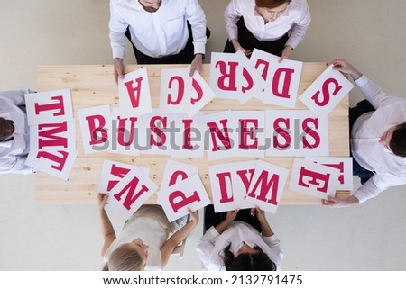 Businesspeople group in business clothes merge letters on paper into word BUSINESS, cooperation unity startup concept